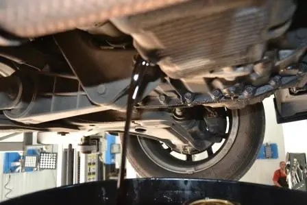 Használt motorolaj kifolyik a leeresztőcsavarból egy edénybe